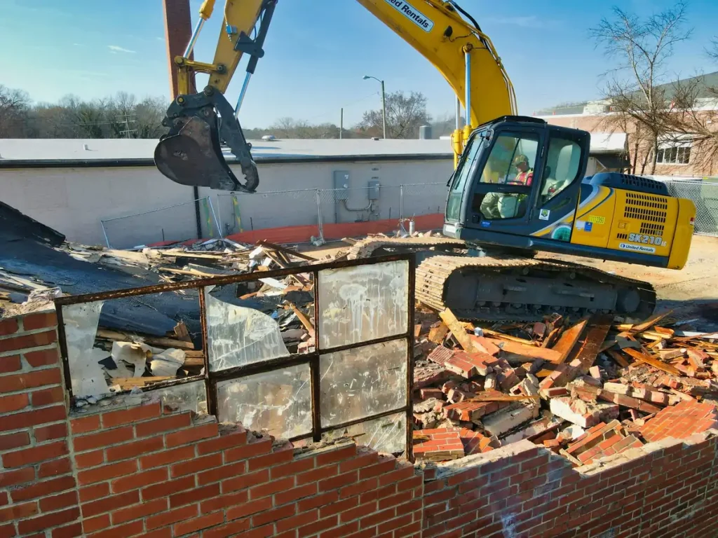 Excavator demolishing a brick building on a teardown site
