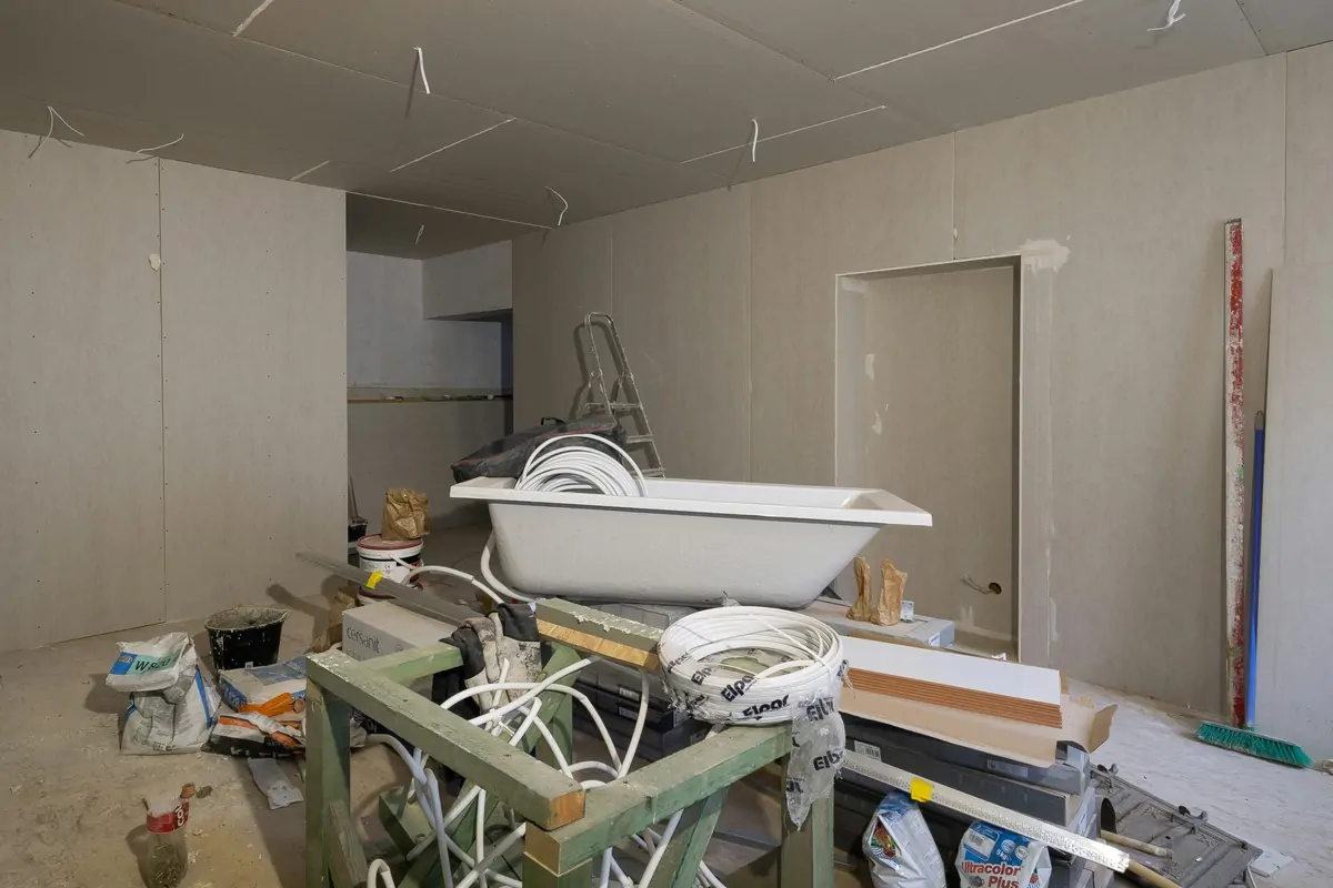 Room stripped back to bare board during an interior renovation, bathtub and materials waiting to be fitted