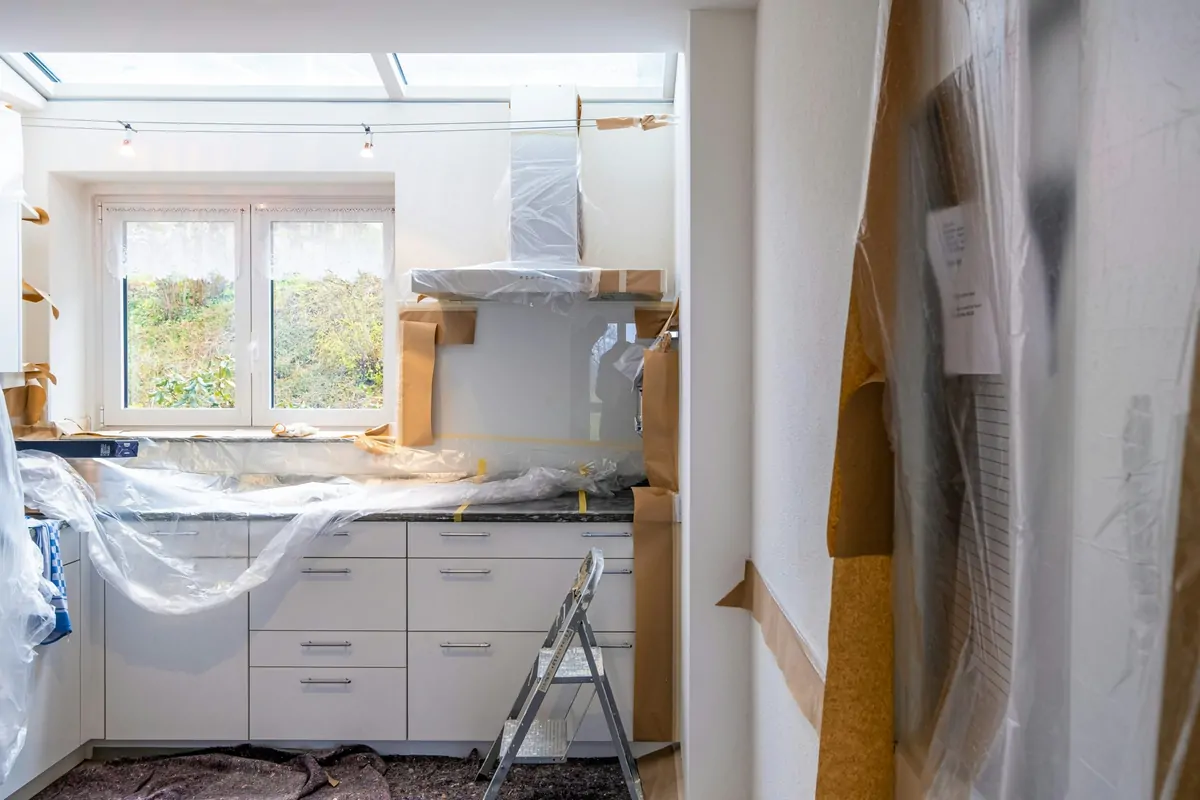 Kitchen sealed with plastic sheeting and masking paper to contain dust during interior work