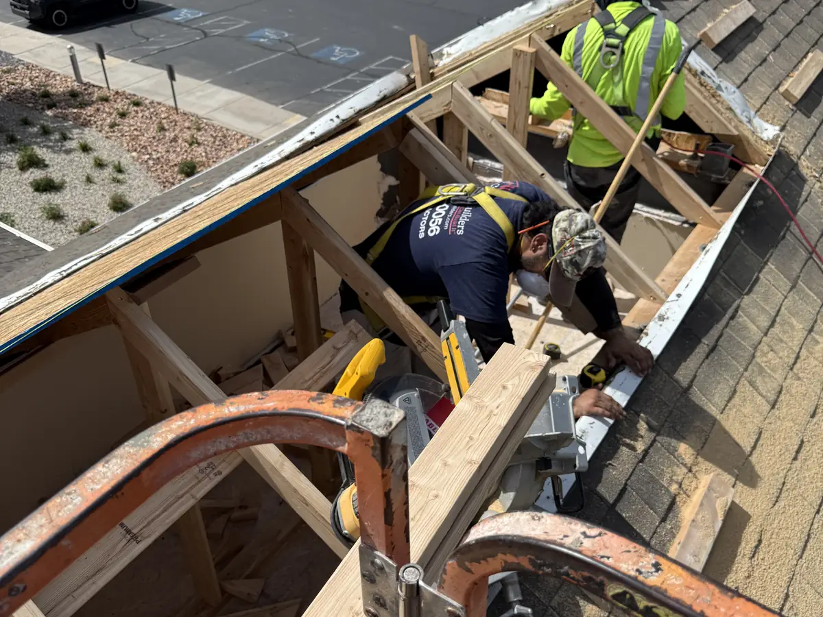 Crew in fall-protection harnesses cutting out roof framing on a commercial building from a man lift