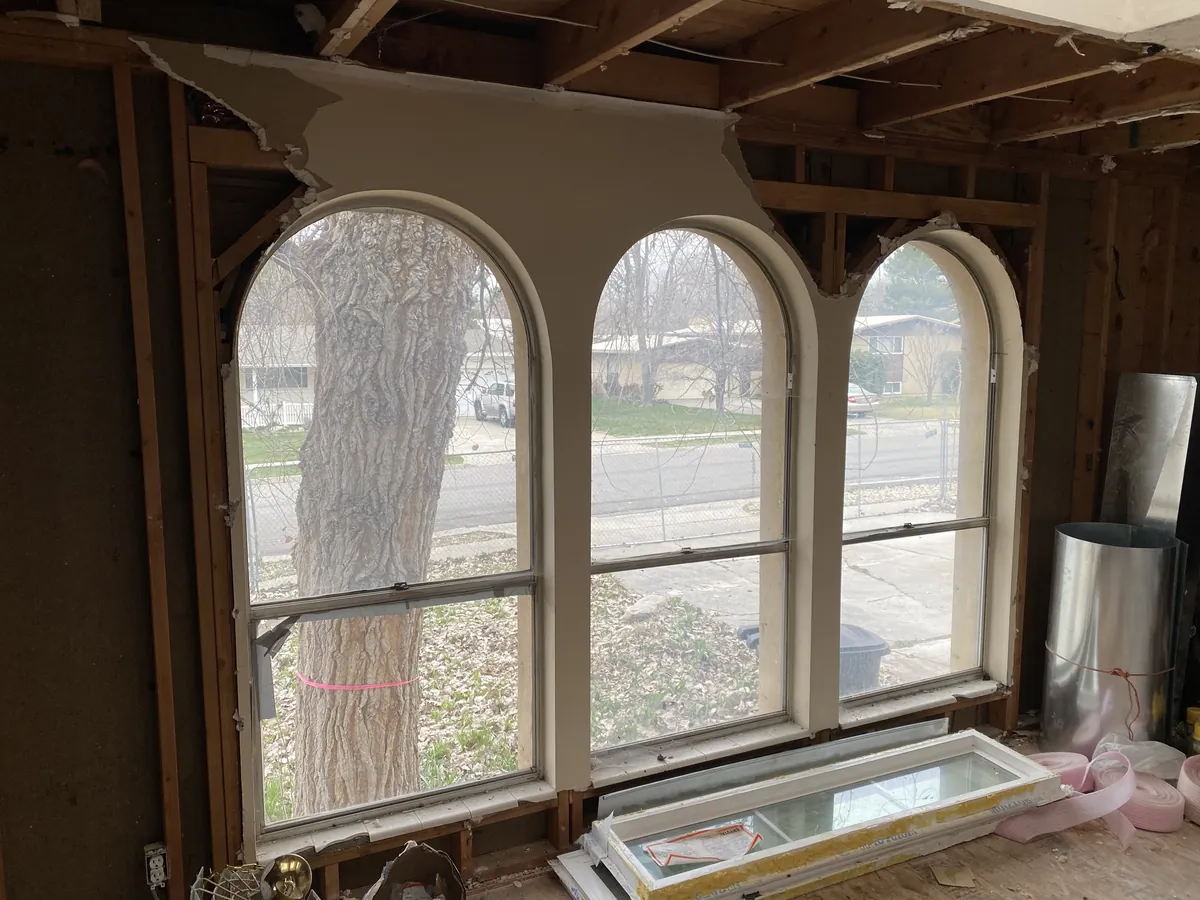 Room gutted to the framing with the ceiling drywall torn out above three arched windows
