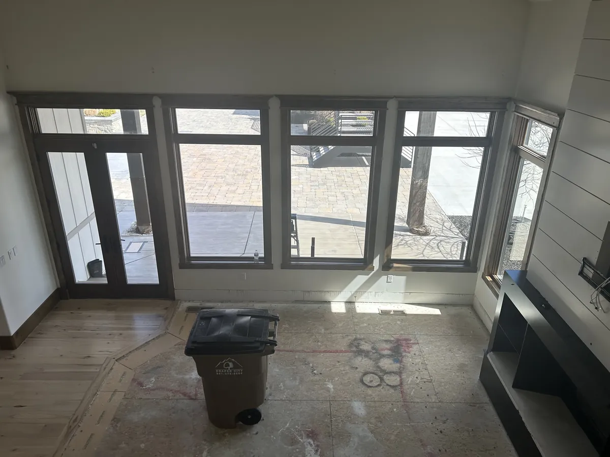Living room with the flooring pulled up to the subfloor and a debris bin in the middle of the room